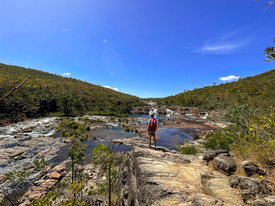 Um homem em pé na frente de corredeiras na trilha da Catarata dos Couros