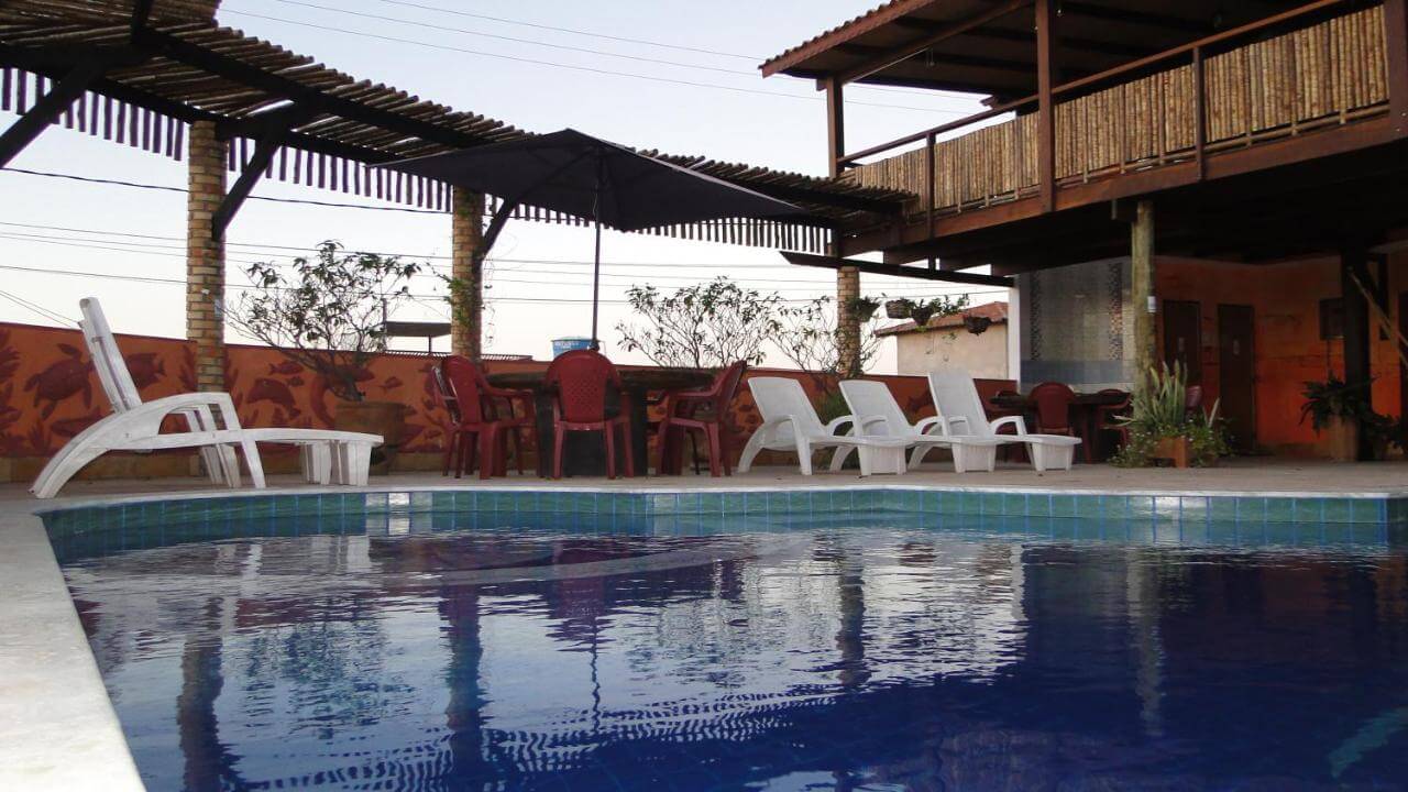 Piscina com espreguiçadeiras, mesas e cadeiras na beira