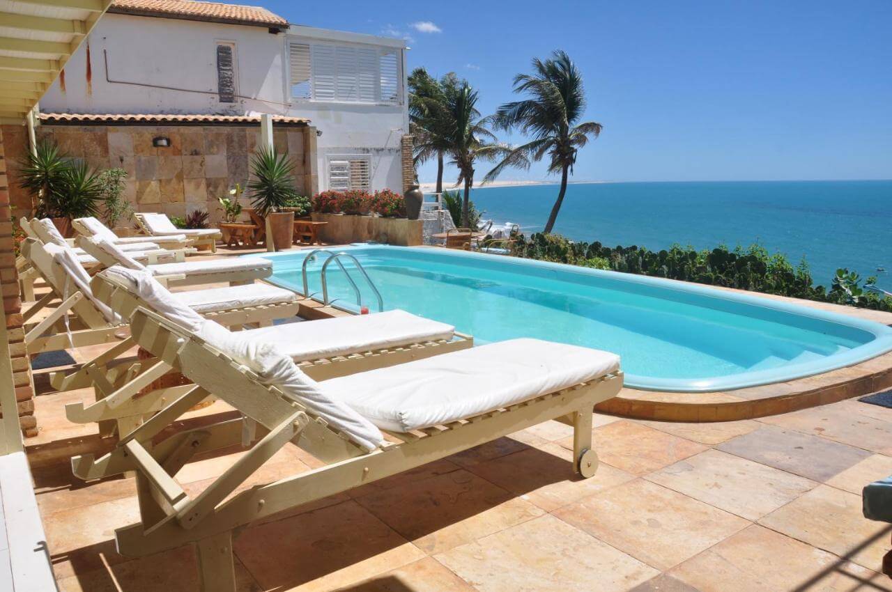 Piscina ao ar livre com espreguiçadeiras e vista para o mar