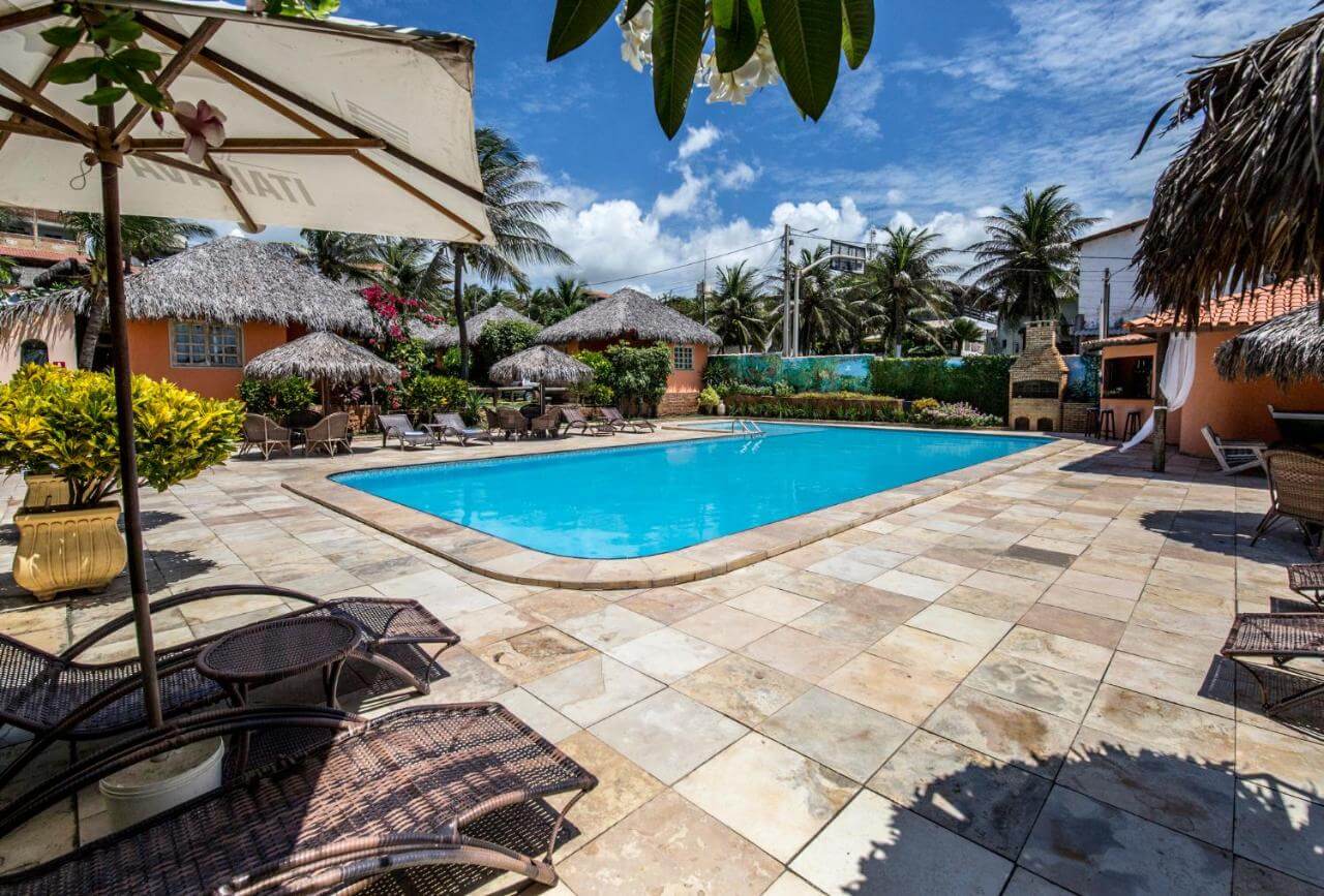Piscina ao ar livre com espreguiçadeiras e guarda-sóis na beirada 