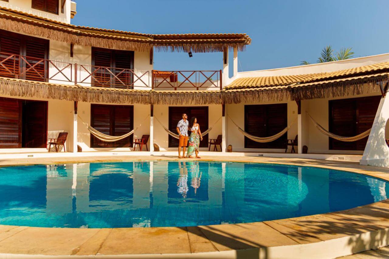 Casal de frente para piscina ao ar livre em pousada em Cumbuco