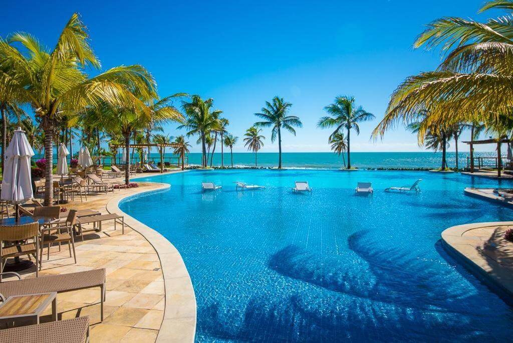 Piscina ao ar livre com borda infinita e coqueiros ao redor