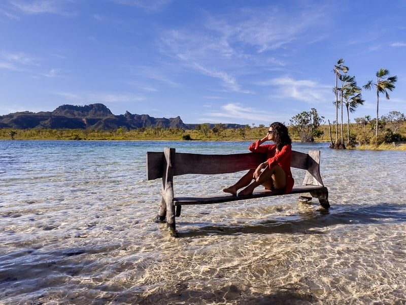Mulher sentada em um banco de madeira na beira da Lagoa da Serra em Rio da Conceição