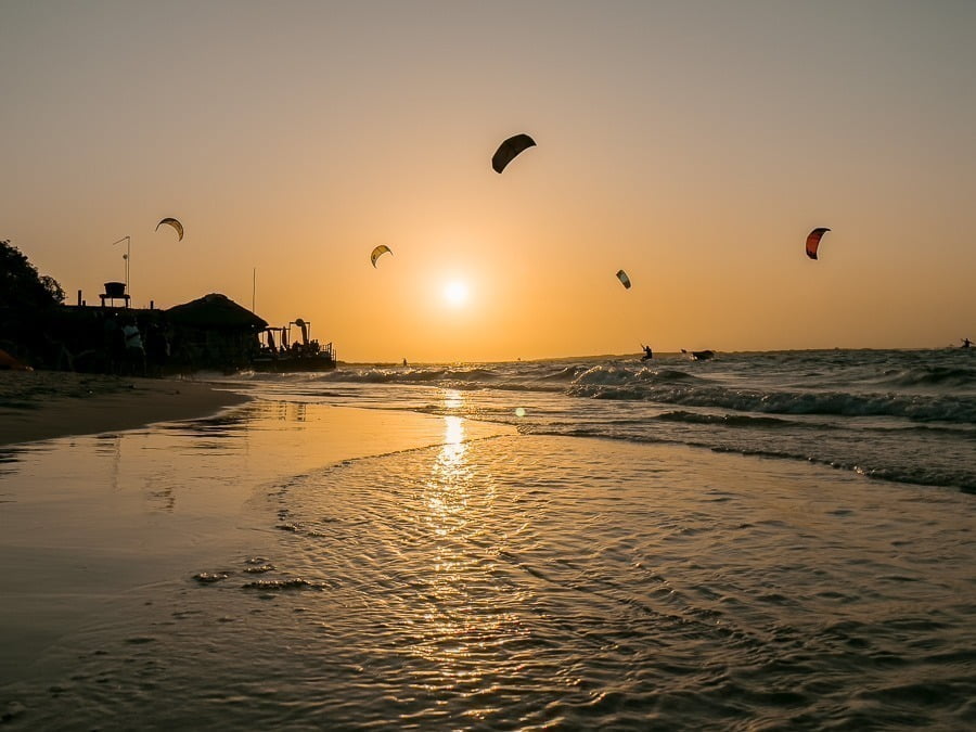Pôr do sol na Praia de Atins com praticantes de kitesurfe no mar.
