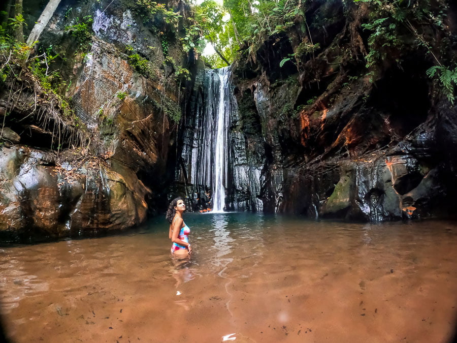 Mulher em poço da Cachoeira do Capelão com queda d'água ao fundo