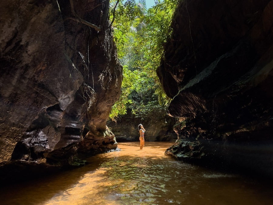 Mulher em pé entre fendas da Cachoeira do Capelão na Chapada das Mesas
