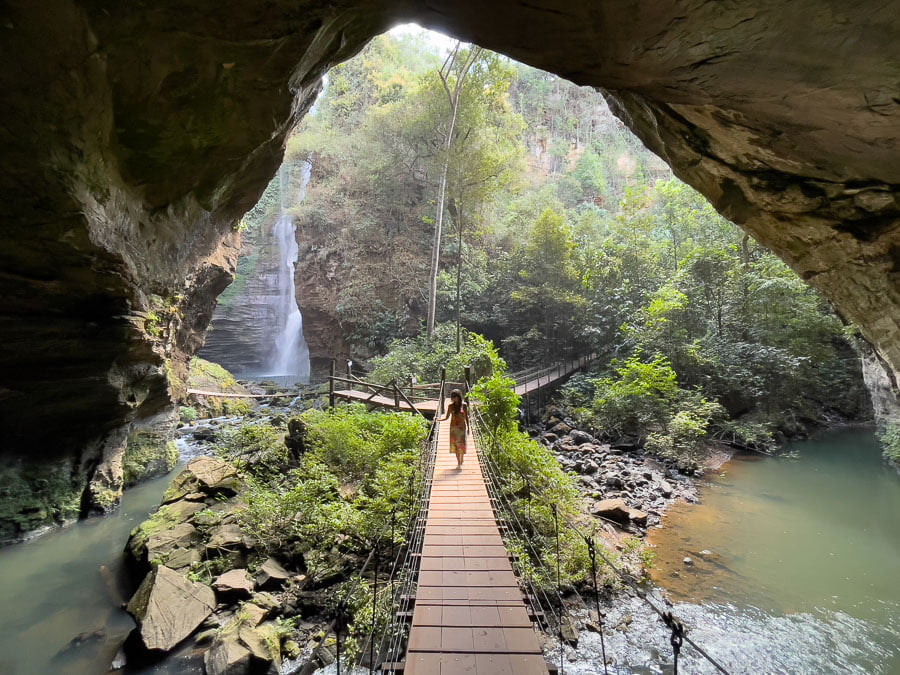 Mulher caminhando na ponte de madeira até a Gruta de Sant Bárbara na Chapada das Mesas