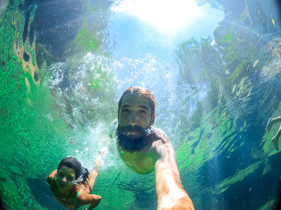 Um casal tirando selfie dentro do Poço Azul na Chapada das Mesas em suas águas azuis cristalinas