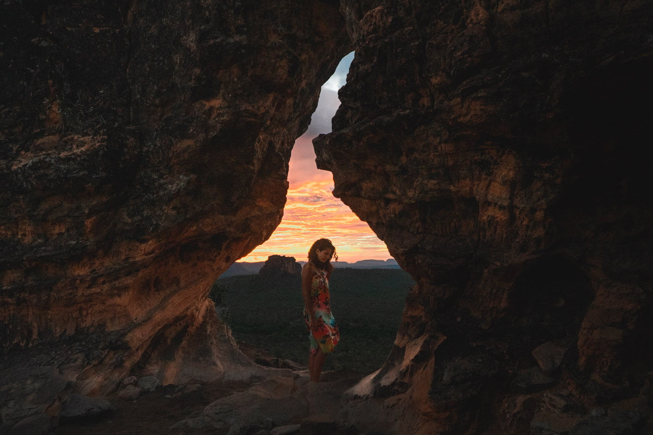 Mulher em pé na abertura do Portal da Chapada observando o nascer do sol