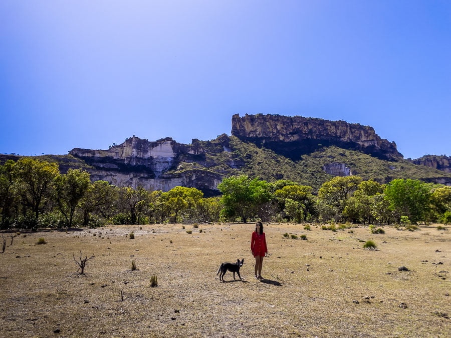 Uma mulher e um cachorro caminhando na trilha do Poço Azul e Morro da Rainha