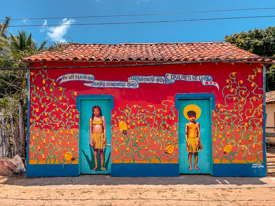 Uma casa colorida em Cajueiro da Praia com duas portas onde uma está desenhado uma mulher e a outra desenhado um homem