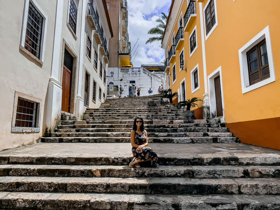 Mulher de vestido sentada em um dos degraus da Rua de Giz em São Luís