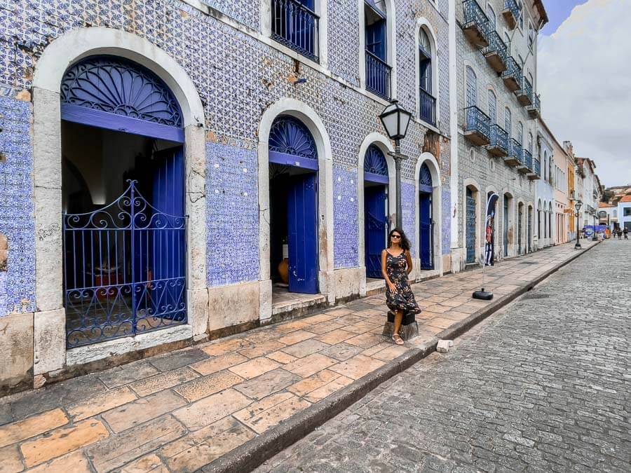 Mulher de vestido encostada em um poste de luz na Rua Portugal em São Luís