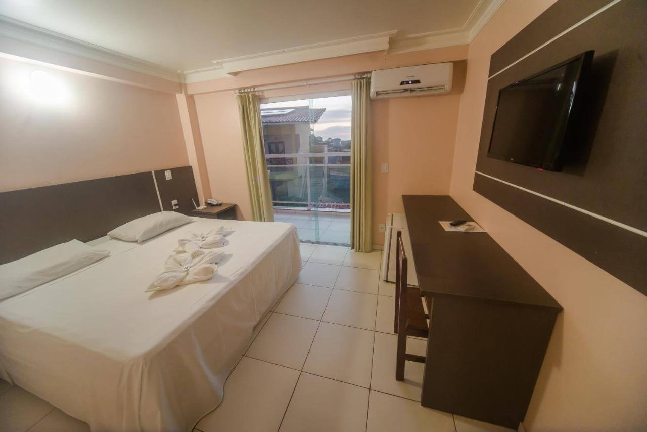 Quarto de casal com escrivaninha, TV e ar condicionado.