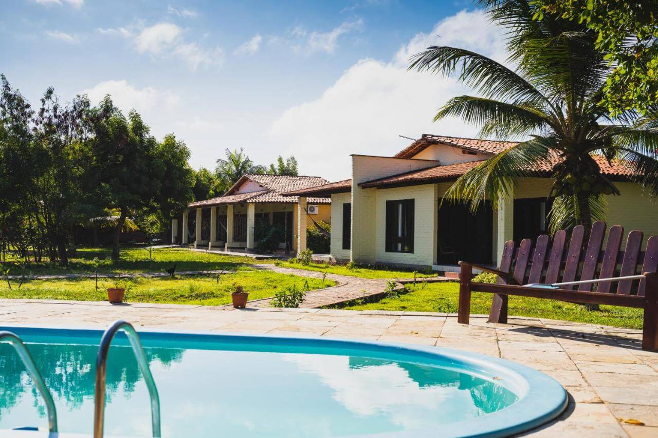 Piscina ao ar livre e ao fundo chalés de pousada em Barreirinhas