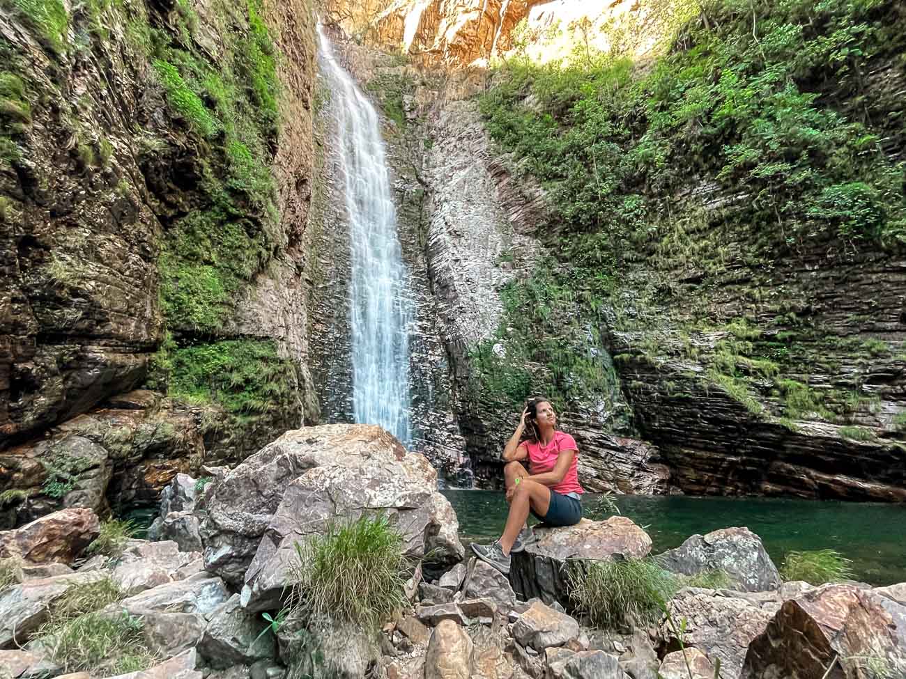 Poço de águas esverdeadas e ao fundo queda d'água entre uma formação rochosa da Cachoeira do Segredo