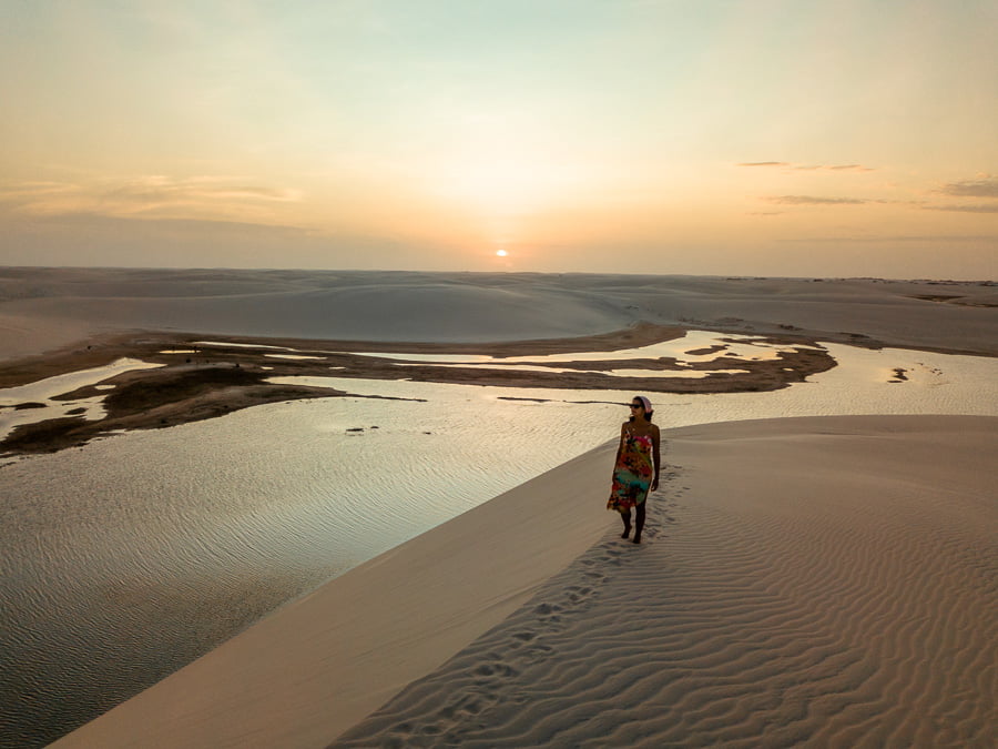 Mulher no topo de uma duna nos Lençóis Maranhenses no Circuito Lagoa Tropical durante o pôr do sol