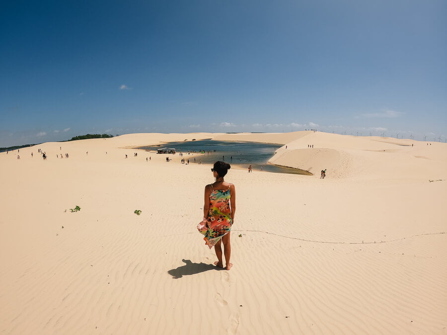 Mulher de costas em duna observando uma lagoa a sua frente na comunidade de Vassouras nos Lençóis Maranhenses