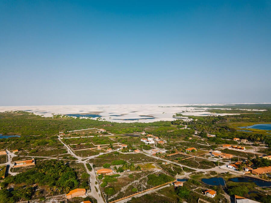 Vista panorâmica de uma parte da cidade de Santo Amaro do Maranhão, rodeada por vegetação e ao fundo das dunas dos Lençóis Maranhenses