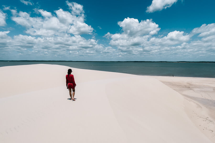 Mulher de vestido vermelho caminhando nas dunas de Ilha do Caju