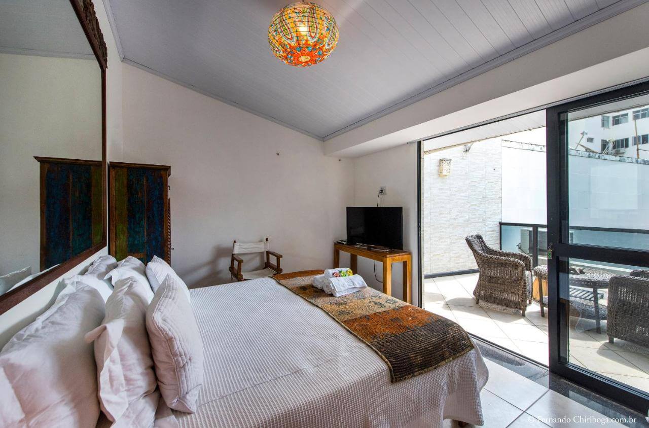Cama de casal de frente para varanda com porta aberta em pousada boutique em Salvador