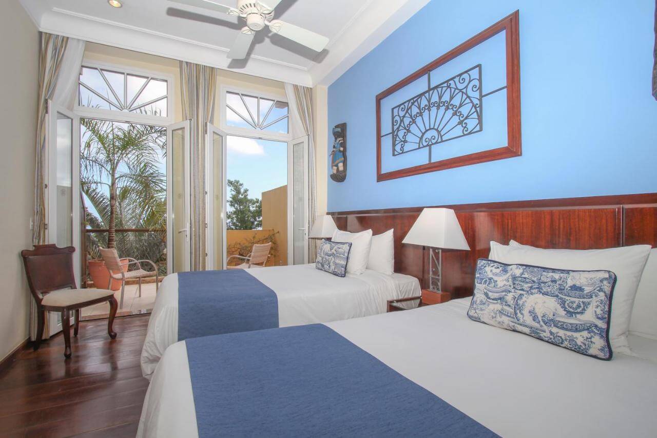 Duas camas em quarto espaçoso e portas abertas para sacada em hotel em Salvador