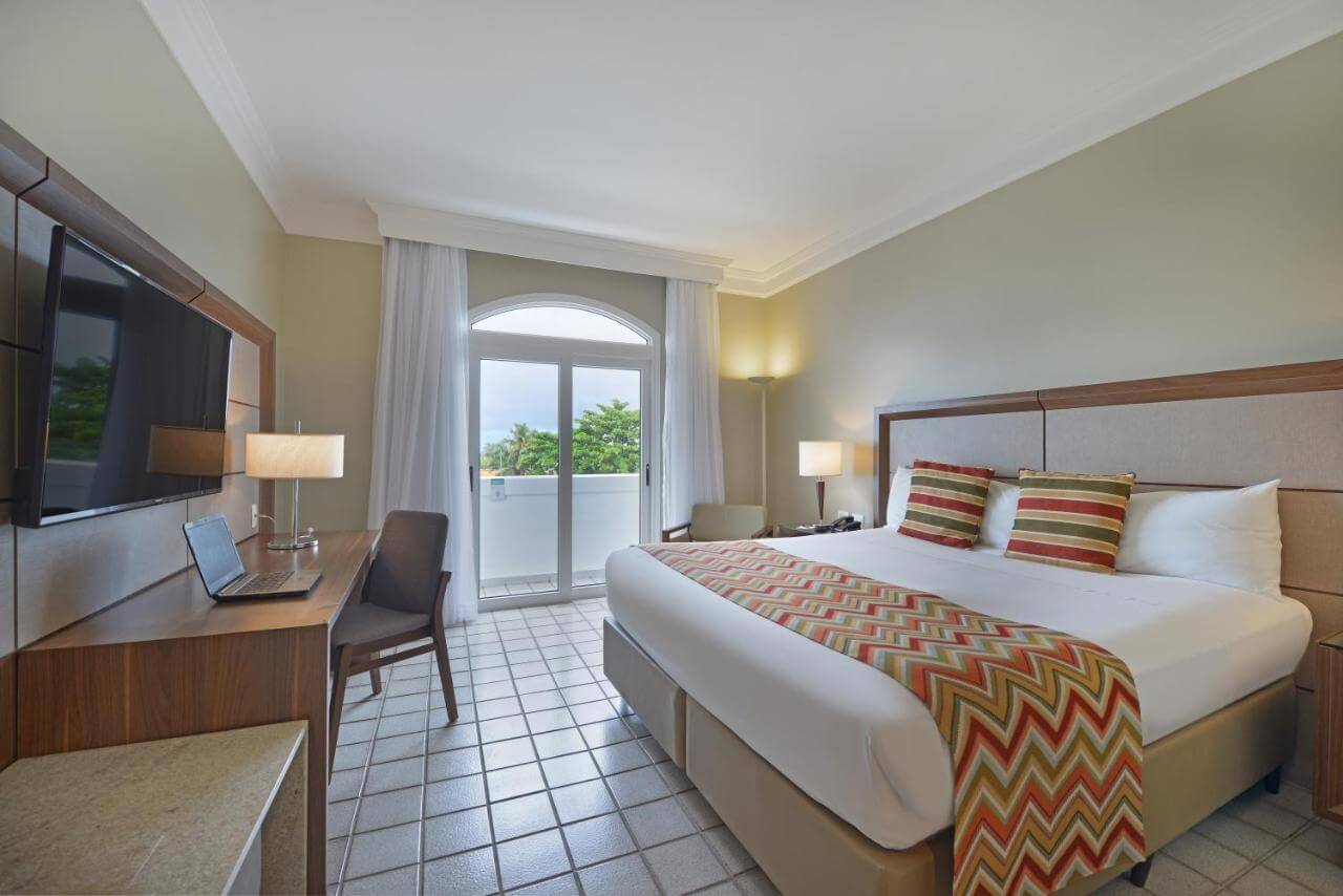 Quarto de hotel em Salvador com cama de casal e porta de vidro com vista para o mar
