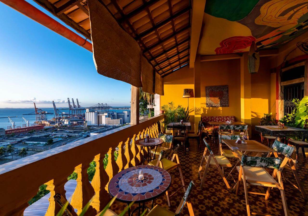 Varanda com mesas e vista de uma parte da cidade de Salvador