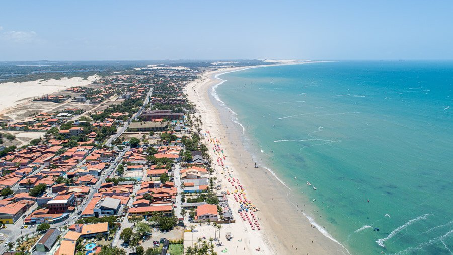 Vista panorâmica da Praia de Cumbuco com o mar à direita e a orla com construção à esquerda