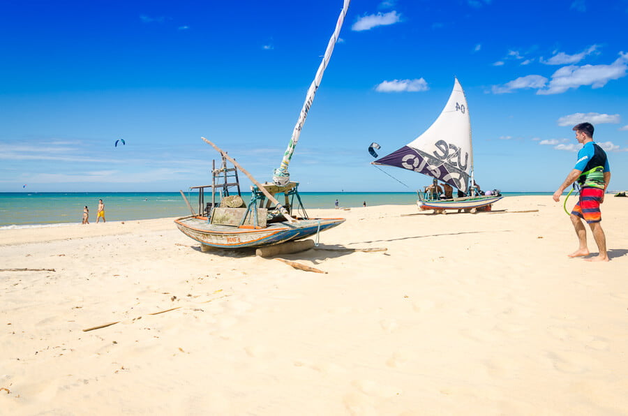 Duas jangadas na areia branca da Praia de Cumbuco. Ao fundo, o mar.