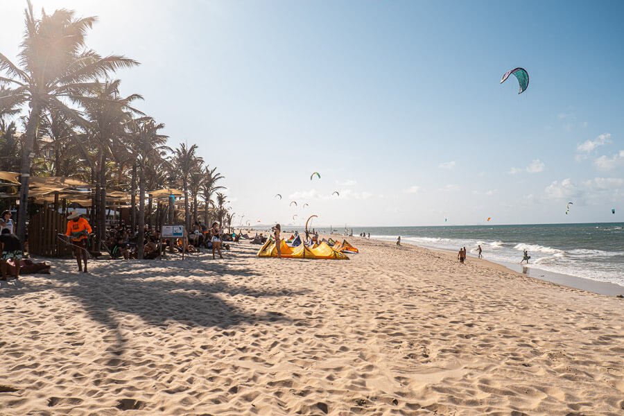 Faixa de areia da Praia de Cumbuco com praticantes de kitesurfe