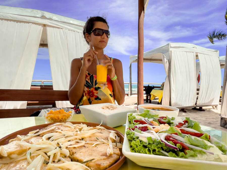 Mulher almoçando pratos de frutos do mar e bebendo suco no restaurante Miramar