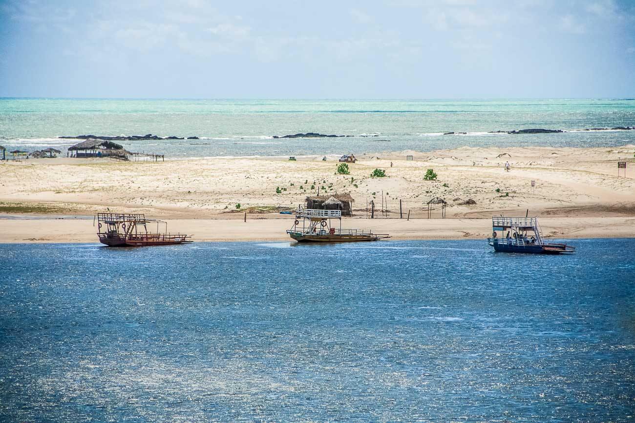 Rio Curimataú em Barra do Cunhaú com barcos atracados e ao fundo faixa de areia e mar ao horizonte
