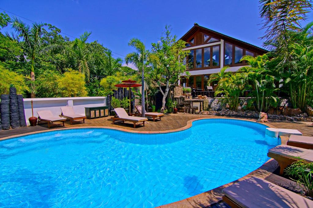 Piscina ao ar livre com canteiro de coqueiros e plantas ao redor.
