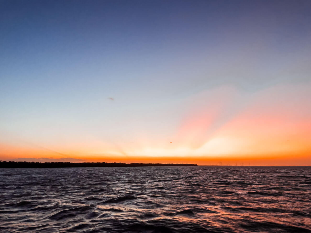 Pôr do sol em tom laranja sobre as águas do rio em Galinhos