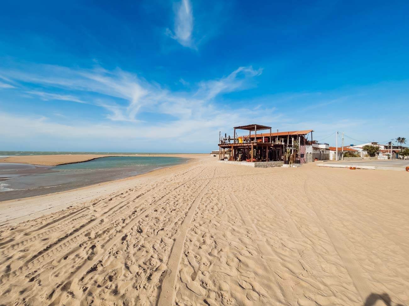 Faixa de areia extensa e larga com uma construção na areia na Praia de Galinhos