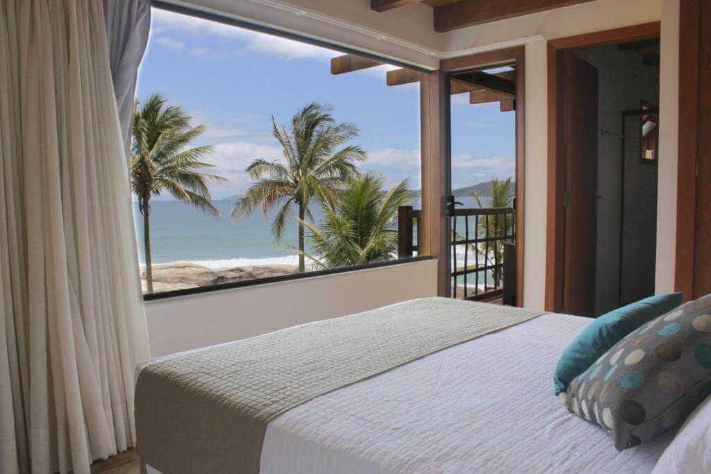 Cama de frente para janela com vista para o mar