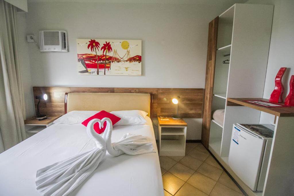 Cama de casal com toalhas no formato de cisnes se beijando