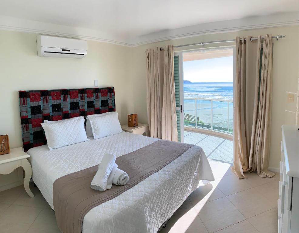 Quarto de casal espaçoso e com decoração moderna com sacada com vista para o mar