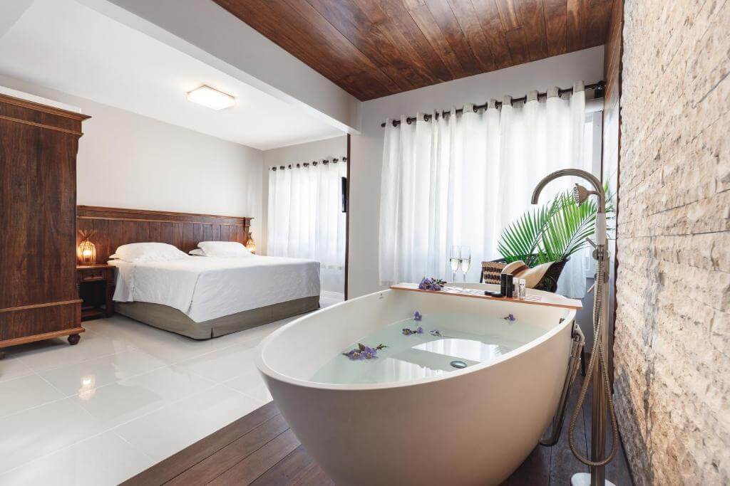 Quarto de casal elegante com banheira de hidromassagem de branca em pousada em Bombinhas