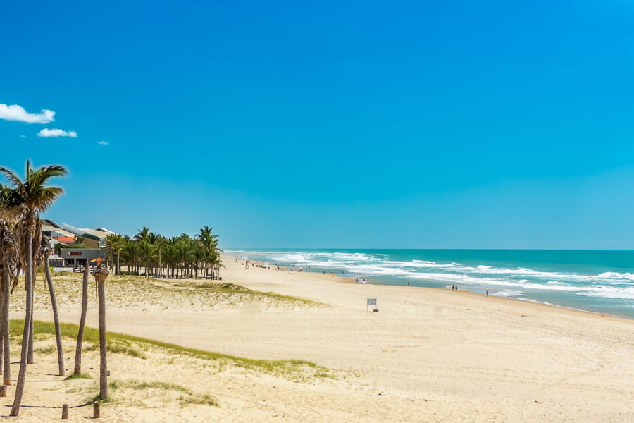 Faixa de areia branca e larga na Praia Porto das Dunas