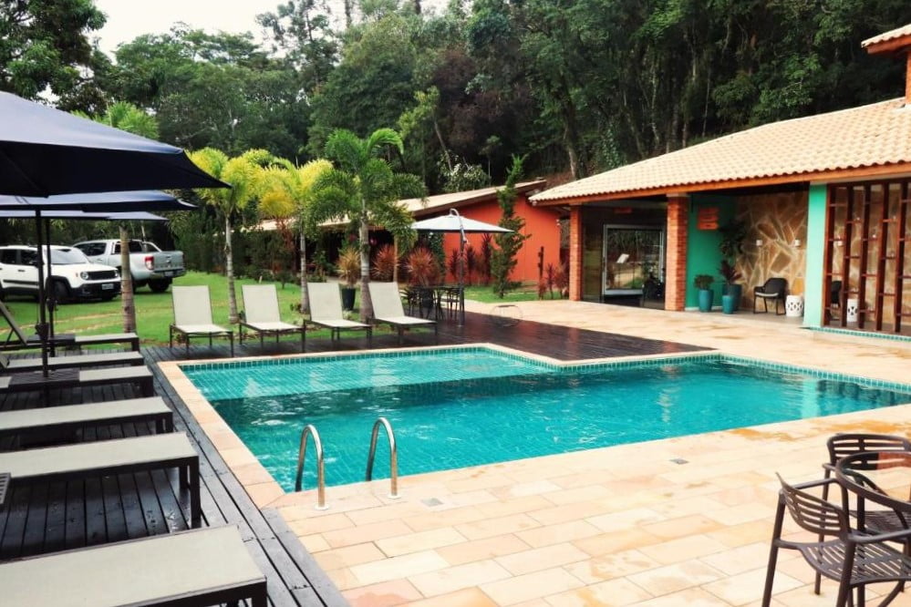 Piscina ao ar livre com espreguiçadeiras ao redor e natureza ao fundo