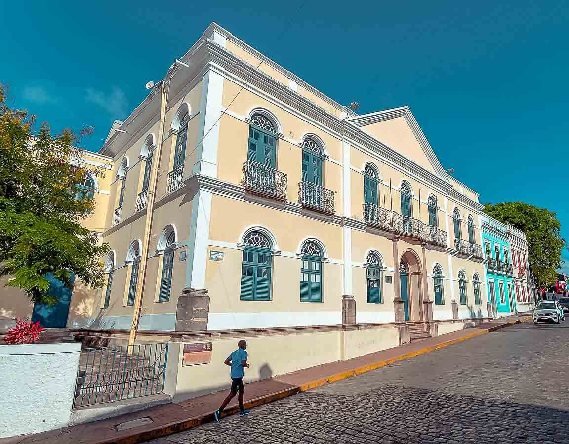 Fachada da Prefeitura de Olinda de arquitetura colonial e dois andares em uma rua de pedra.