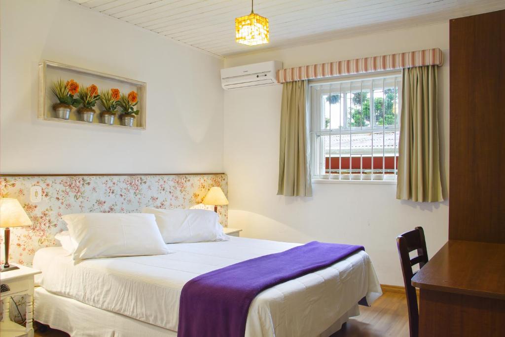 Quarto de casal com decoração em tons claros e estampas de flores