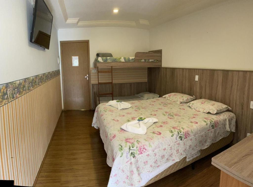 Quarto de casal com piso de madeira e ao fundo uma beliche