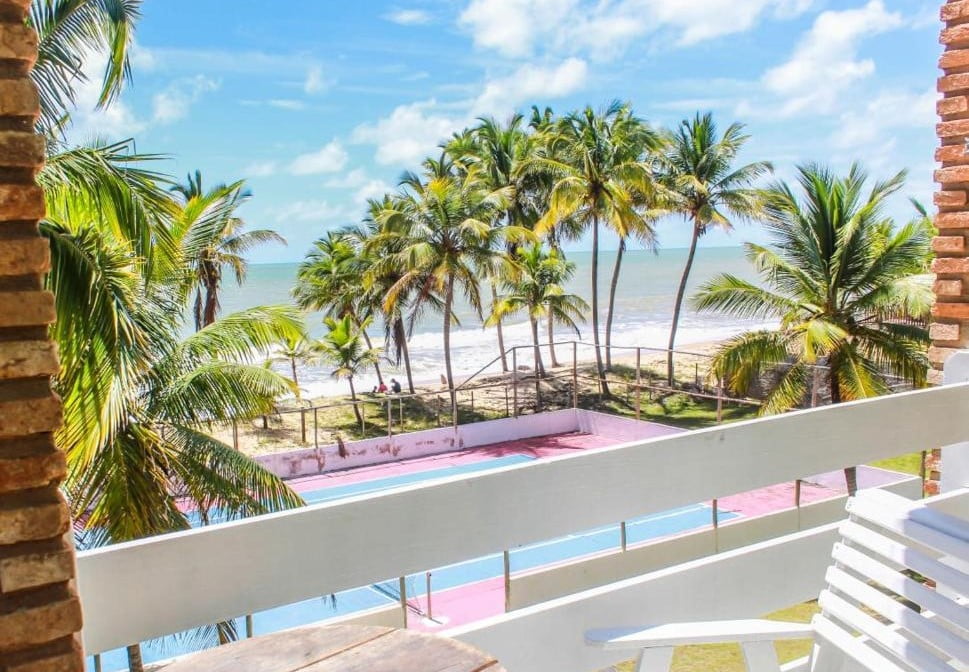 Sacada com vista para quadra esportiva e ao fundo coqueiros e o mar em Prado Bahia