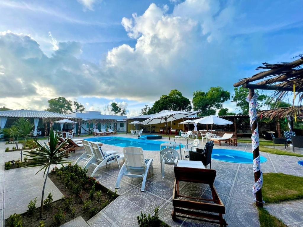Vista de área externa com piscina, espreguiçadeiras e guarda-sóis em pousada