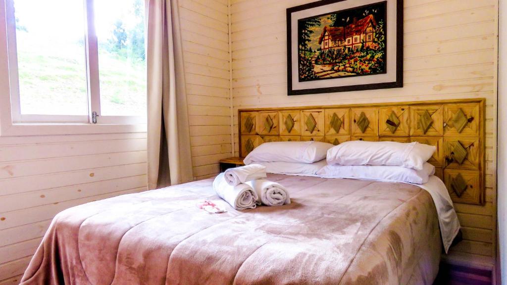 Cama de casal com cabeceira de madeira e paredes de madeira em pousada em Urubici