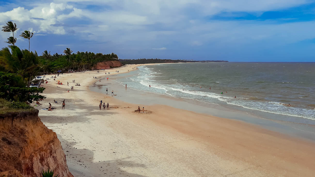 Faixa de areia larga e extensa da Praia Barra do Cahy e ao fundo falésias