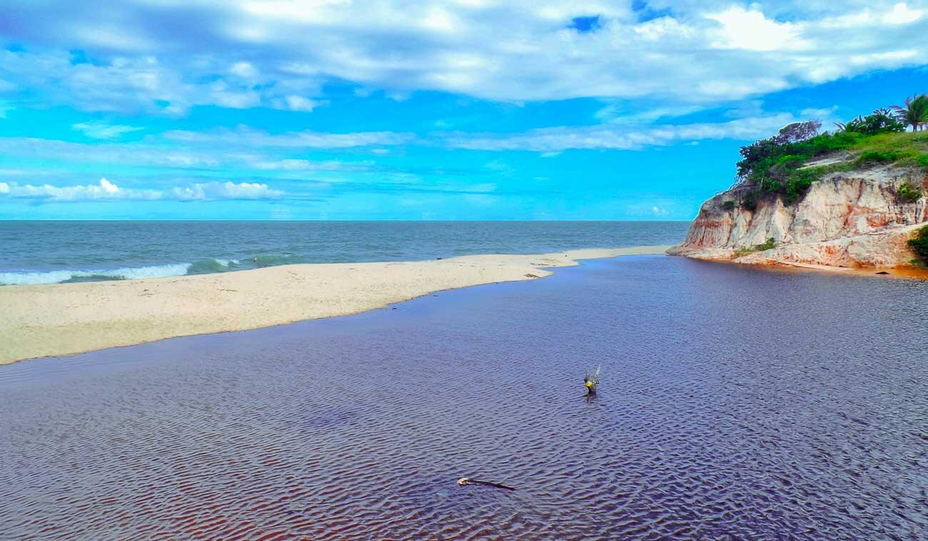Encontro do rio com o mar ao fundo na Praia das Ostras em Prado